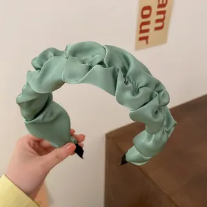 Close-up of sage green ruched satin headband showing high-top design and soft texture