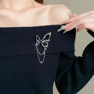 Nahaufnahme einer eleganten schwarzen Schmetterlingsbrosche mit silbernen Ketten