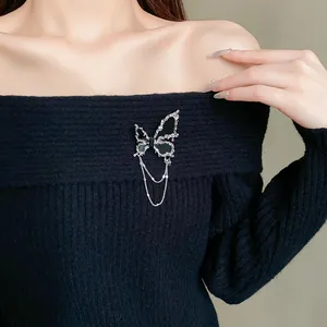Detailansicht der silbernen Schmetterlingsbrosche mit schwarzen Steinen am schwarzen Pullover