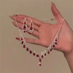 Detailed view of rhinestone water-drop necklace and earrings jewelry set in hand.