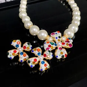 Detailed shot of colorful rhinestone flower clip-on earrings and white pearl necklace.