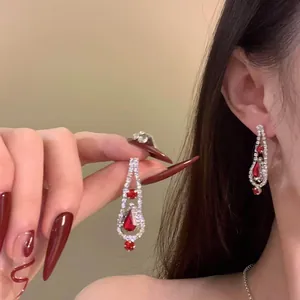 Close-up of elegant teardrop fringe earrings with red gemstones and crystal accents