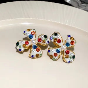 Detail view of multi-colored rhinestone and pearl flower clip-on earrings on a plate