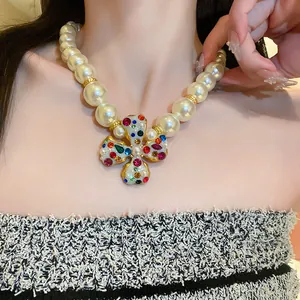 Detail view of elegant large pearl necklace featuring a colorful rhinestone cross flower pendant