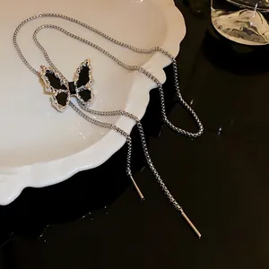 Elegant silver butterfly lariat necklace with black wings on a white ceramic plate