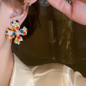 Detailed view of a flower-shaped ear clip with colorful rhinestones and pearls on a model