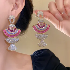 Detail view of exquisite fan-shaped drop earrings with vibrant purple and magenta crystals