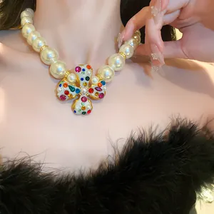 Close-up of elegant pearl necklace with colorful rhinestone flower pendant on model