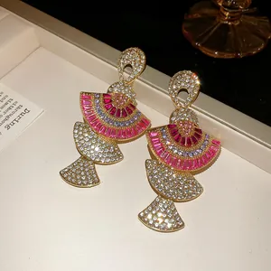 Detailed view of luxury gold fan-shaped earrings with pink and white sparkling rhinestones