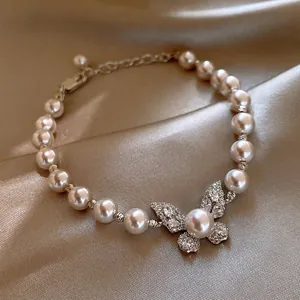 Detailed view of white pearl bracelet featuring a sparkling crystal butterfly charm