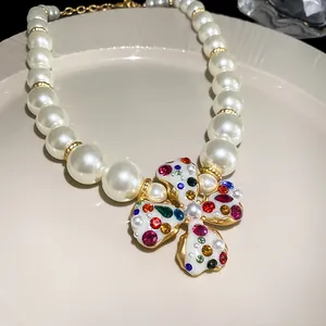 Macro view of a luxurious pearl necklace with a vibrant rhinestone flower pendant