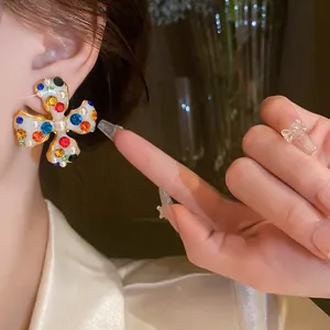 Close-up of vibrant floral clip-on earring with multi-colored crystals and pearls