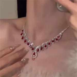 Close-up of vintage teardrop red gemstone necklace with rhinestones on model neck.