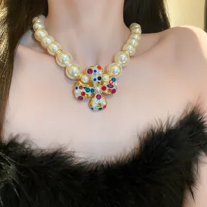 Detail view of luxury chunky pearl necklace with a colorful rhinestone flower pendant