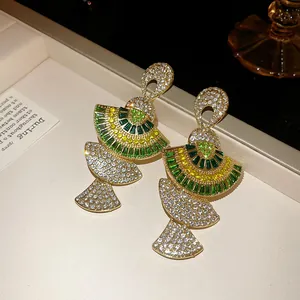 Close-up detail of vintage fan-shaped earrings encrusted with green and clear crystals
