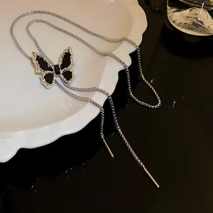 Detailed macro view of a silver butterfly necklace with black inlay on a white plate