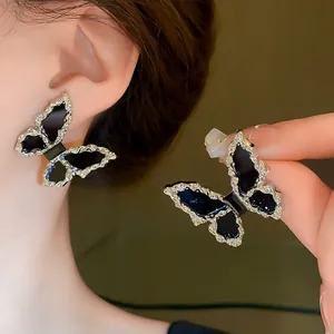 Detailed view of butterfly earrings with black wings and textured silver border.