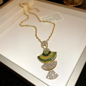 Macro detail view of a vintage fan-shaped pendant necklace with green and clear sparkling stones