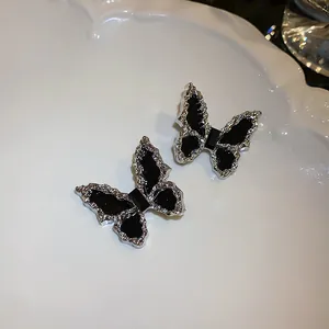 Detailed view of silver butterfly stud earrings with wrinkled black inlay