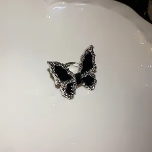 Macro view of elegant silver-tone butterfly jewelry with black enamel on a white plate