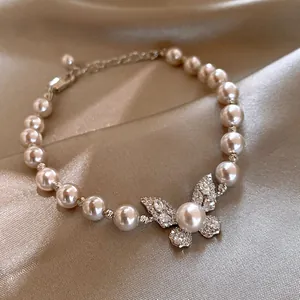 Close-up of elegant butterfly pearl bracelet with sparkling crystals on satin background