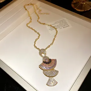 Close-up of gold fan-shaped pendant necklace with colorful crystals and baguette stones.