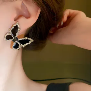 Macro close-up view of a large black butterfly earring featuring a silver crinkle texture edge