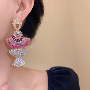 Close-up view of elegant fan-shaped drop earrings with colorful crystals worn by a model