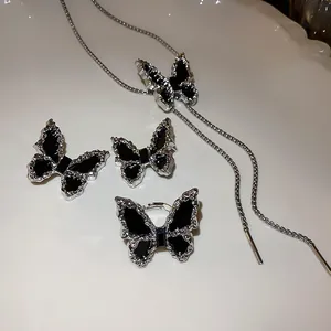 Detail of silver pleated black butterfly jewelry set with earrings, ring, and necklace.