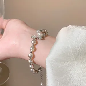 Close-up view of a French retro pearl bracelet with a sparkling rhinestone butterfly charm.