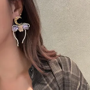 Detailed close-up showing sweet pearl bear and purple bow drop earrings worn by a model