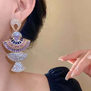 Detailed shot of vintage fan-shaped gold earrings with colorful rhinestones on an Asian model
