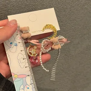 Detail shot of asymmetric pink bow teddy bear earrings with pearls and heart crystal