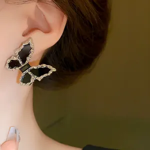 Detail shot of a silver butterfly earring with black enamel on a woman's ear