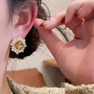 Gros plan d'une boucle d'oreille élégante en forme de marguerite dorée 18 carats