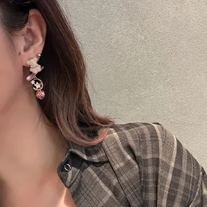 Close-up detail of a cute teddy bear drop earring featuring rhinestones and a pink heart gem