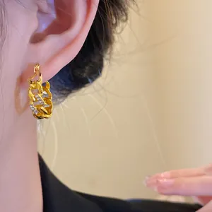 Close-up detail of a gold hollow chain hoop earring inlaid with small diamonds on an ear.