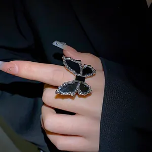 Detail shot of a bold silver-tone butterfly ring with black enamel on a model's hand