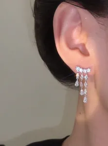 Detailed close-up of a sparkling 18k gold plated earring with water drop zircon tassels.