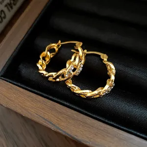 Close-up of gold hollow chain link hoop earrings with sparkling rhinestones