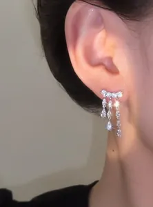 Close-up detail of luxurious 18k gold plated zircon teardrop tassel earrings worn on ear