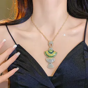 Detailed view of a vintage fan-shaped necklace featuring sparkling green and clear stones.