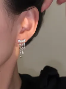 Elegant macro detail showing sparkling zircon teardrop tassel earrings on a model ear