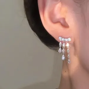 Detail view of shimmering 18k gold plated water-drop zirconia tassel earrings on ear.