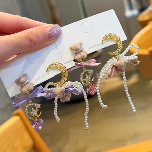 Close-up of sweet bear dangle earrings with pearls, bows, and crescent moon charms.