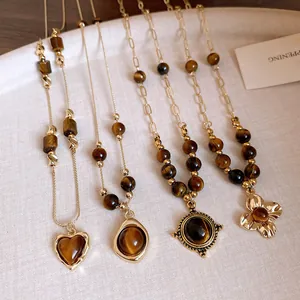 Detailed view of tiger eye stone necklaces with heart, circle, and flower gold pendants.