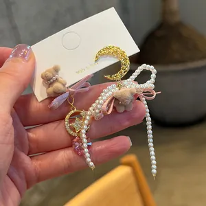Detail of cute bear and pearl pendant earrings with gold moon and star accents