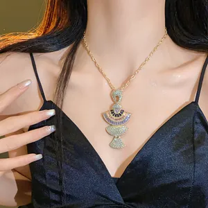 Detailed view of gold necklace featuring layered fan-shaped pendants with crystals.