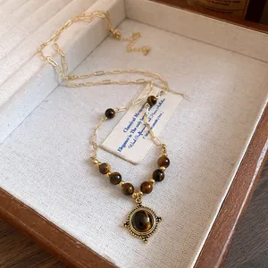 Close-up view of a vintage gold necklace with tiger eye beads and round pendant jewelry