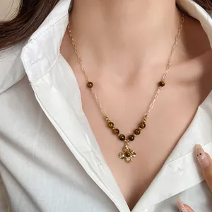 Close-up of vintage tiger eye beaded necklace on model with white shirt